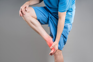 Joint inflammation, foot pain, man suffering from feet ache on gray background, podiatry concept