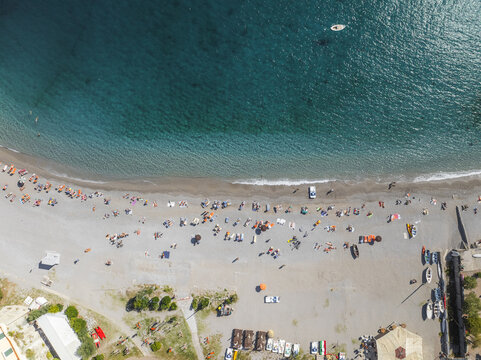 Aerial view of the beach where the turquoise sea gently kisses the sandy shore, dotted with sunbathers and boats, framed by the rugged coastline, Erchie, Amalfi Coast, Italy.
