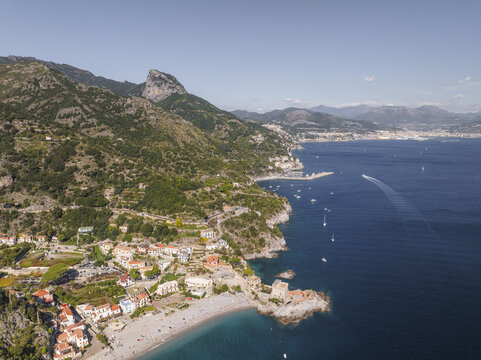 Aerial view of rugged mountains cascade into the azure sea, cradling the charming coastal village below, Erchie, Amalfi Coast, Campania, Italy.