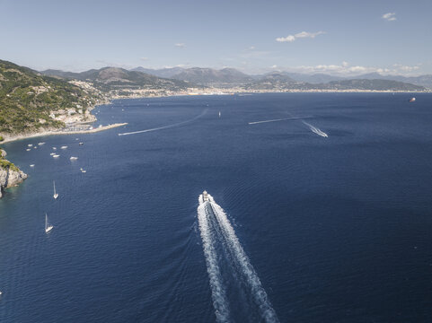 Aerial view of the azure sea dotted with white boats against the backdrop of rugged cliffs and the distant mountains, Erchie, Amalfi Coast, Italy.