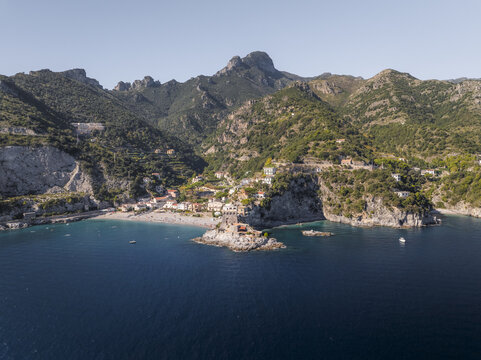 Aerial view of a picturesque coastal village nestled between rugged mountains and a serene bay with crystal-clear turquoise waters, Erchie, Amalfi Coast, Italy.