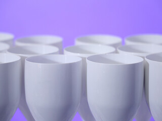 Row of white glasses. stock A row of perfectly aligned white glasses creates a harmonious and modern visual effect. The glossy surfaces reflect the soft light, giving the scene a clean, sophisticated,