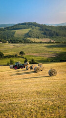 Tractor working on hay field in summer countryside with hills © Vectornaut