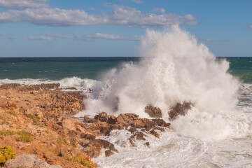 Fototapeta premium Stormy seascape with waves crashing against rocky shore and high white foam splashes
