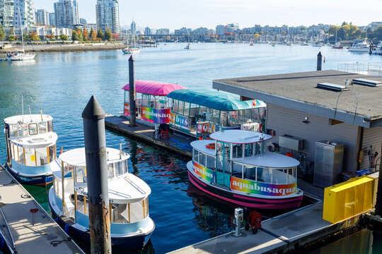 Colorful Aquabus ferries with rainbow canopies docked at Granville Island pier with Vancouver harbor