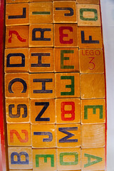 Naklejka premium Prague, Czechia - September 20, 2025: Vintage wooden alphabet Lego blocks arranged on table in nostalgic warm light