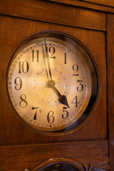 Classic wooden wall clock with aged dial and vintage charm, illuminated by soft warm light. Ideal for antique interiors or nostalgic home decor themes.