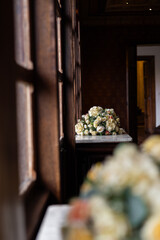Soft yellow roses and white blooms arranged together on a marble surface in a warm wooden interior filled with natural light.