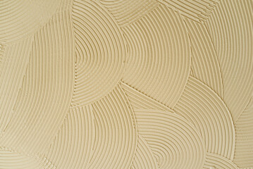 Beige textured background with abstract curved pattern of plaster or putty