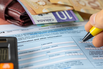 Canada taxes. A man manually fills out a tax return and  benefits form. Financial concept. close...
