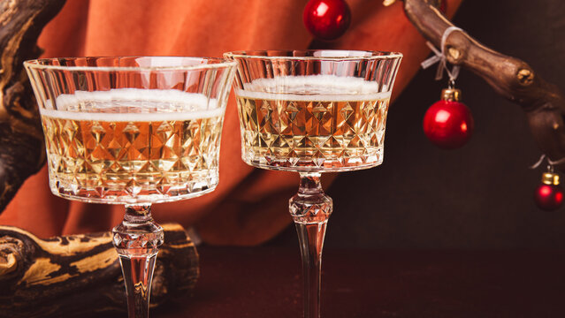 Champagne in wine glasses and Christmas decorations on red table. Happy New Year. Festive party. Greeting card or invitation with copy space for text.