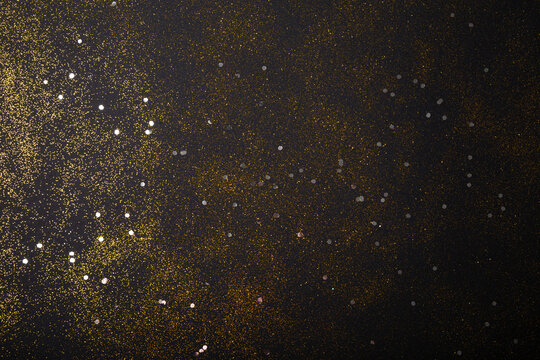 Black festive christmas background. Abstract scattering of gold sparkles on black. Holiday backdrop