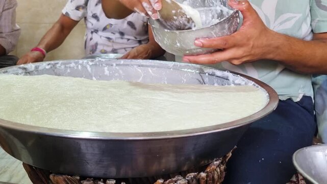 Man cutting away curd chunks for making traditional indian sweet drink lassi popular in the hot summer months as a street food snack