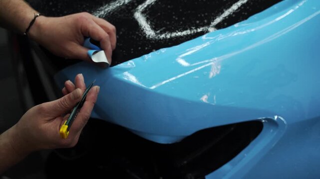 PPF Trimming with Precision Knife 4k video. Knife trimming in vinyl wrap detailing is crucial for perfection. Sharp blade is used to finalize the detailing process, cutting PPF wrap.