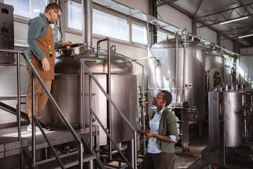 Brewery workers inspecting fermentation tanks for quality control