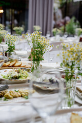 An elegantly decorated banquet table with delicious food and fresh chamomile centerpieces.