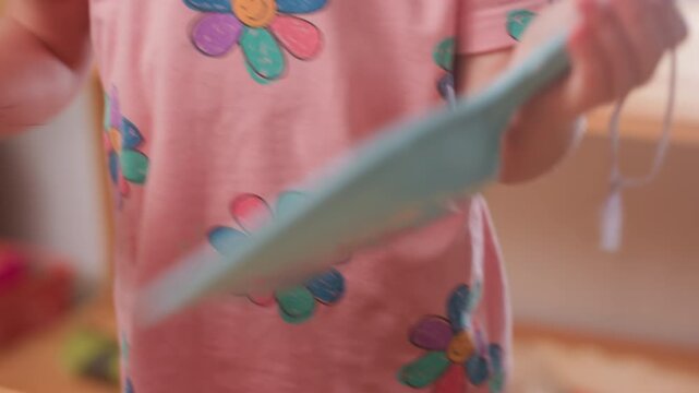 close up child in pink floral shirt cleaning wooden table with brush and parker during classroom tidy routine, focused hands glide over surface, kindergarten setting builds responsibility