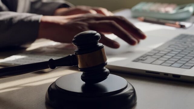 Gavel on desk with lawyer hand typing on laptop. Concept of digital law, legal services, and modern justice system.