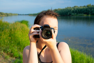 Lady with camera on riverside. Sunny outdoor photography
