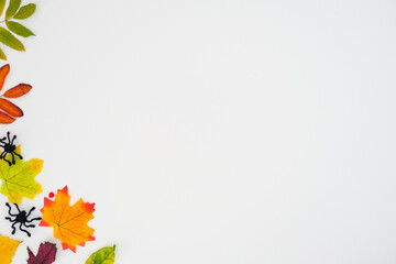 Horizontal autumn banner with a fallen colorful leaves and black spiders on white background with place for text