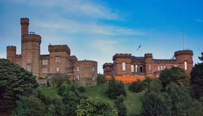 Majestic medieval castle perched atop a lush, verdant hill, its turrets and towers commanding the surrounding landscape under a vibrant blue sky. © paws and prints