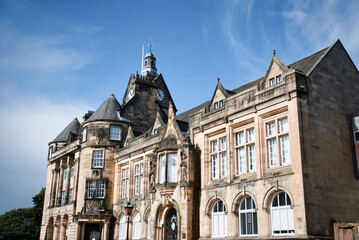 Fototapeta premium Majestic 19th century town hall with ornate architecture and a clock tower, set against a clear blue sky in a historic European city.