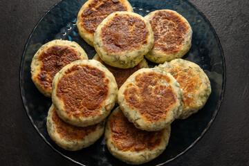Cottage cheese pancakes or fritters with herbs, green onions, and parsley. Pan-fried syrniki with dill. A healthy breakfast or a dietary lunch. Copy space.