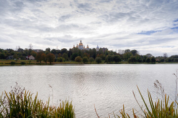 The church is located among the trees. In front of it is a lake. Landscape.