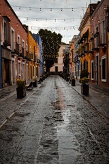 Fototapeta premium Vibrant nighttime scene of a picturesque, rain-soaked alleyway in a historic European town, illuminated by twinkling string lights and warm building colors.