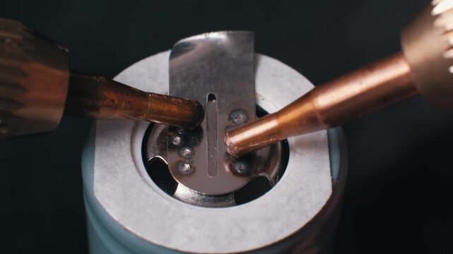 Close-up macro of spot welding a nickel tab to a green lithium-ion battery terminal with copper electrodes, generating sparks and weld points for pack assembly.