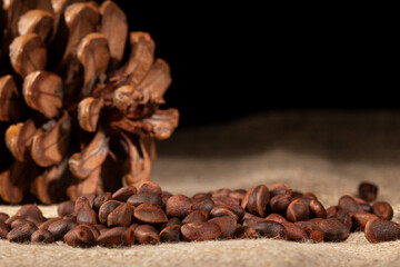 Close-up of a pine cone and pine nuts arranged on a rustic burlap napkin