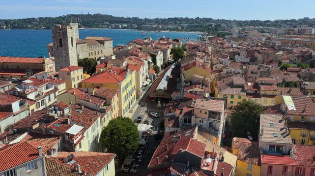 Aerial drone view of Antibes Old Town rooftops with Chateau Grimaldi and church towers facing the Mediterranean Sea