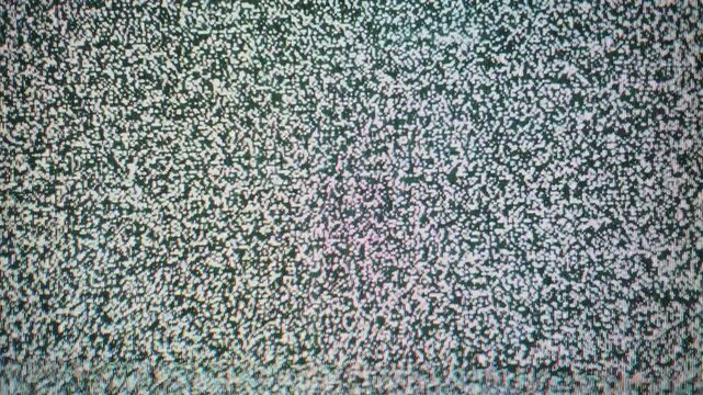 Extreme close-up macro shot captures the chaotic flickering texture of analog TV static. White and grey pixels dance randomly, creating an abstract visual noise pattern from signal interference.