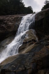 Cascading waterfall plummeting over rocky cliff in lush, verdant forest.