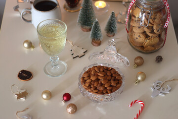 Cookie jar, tea, wine, nuts, books, lit candles and Christmas decorations on the table. Cozy Christmas hygge at home. Selective focus.