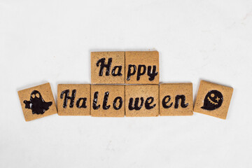 Halloween Holiday. Cinnamon cookies with black marmalade filling in the shape of Happy Halloween and ghosts. White background. Top view