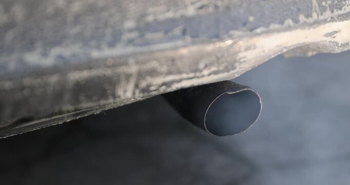 blue harmful smoke from the muffler of an old car with an inoperable or not installed filter for cleaning exhaust gases, an old pipe in the car for releasing exhaust gases from the car engine