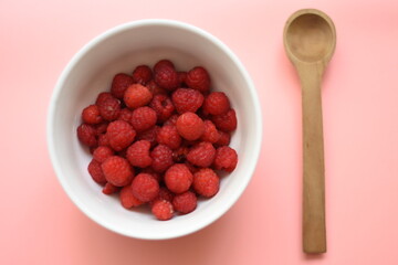 Bowl of fresh raspberries on white background – healthy and natural food