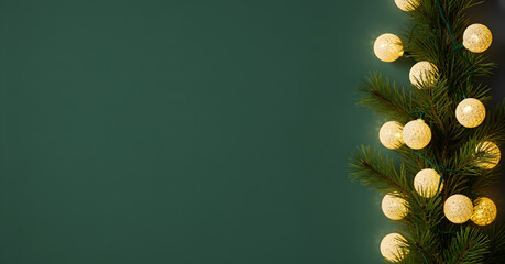 Evergreen branch with warm string lights on green background with wide copy space for winter holiday banner greeting card