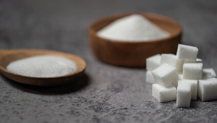 Sugar In Wooden Spoon and sugar cubes on gray background. Close up,Pile of sugar cubes on the table