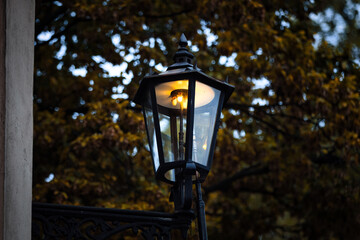 Warm autumn evening illuminated by a vintage street lamp casting a cozy glow in the park.