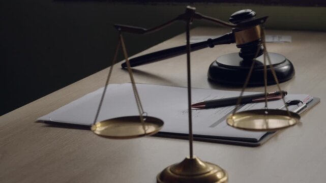 Symbolic composition featuring hand signing legal contract alongside justice scales and gavel.