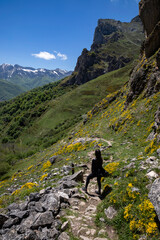 Fototapeta premium Adventurous young woman trekking a mountain trail with stunning views, breathing fresh air and connecting with nature on a sunny day adventure