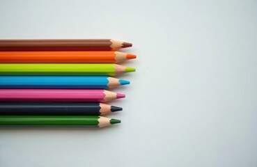 Obraz premium Colored pencils arranged in row on white background. Different colored pencil tips visible. Pencils neatly placed side by side. Various colors like green brown orange blue pink seen. Art, drawing