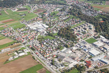 Aerial view of town with houses, streets, and fields. Drone photo of urban landscape showing modern buildings, green areas, and suburban architecture pattern.