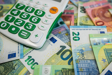 Stack of Euro banknotes with blue calculator symbolizing finance, accounting and money planning