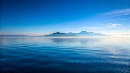 Serene ocean landscape with distant misty mountains and calm water