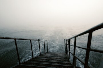 Obraz premium Serene wooden steps leading into tranquil misty waters at dawn