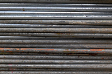 Stacked gray metallic pipes with surface texture and industrial wear patterns