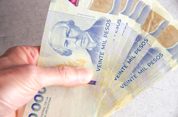 Female hands holding a bunch of twenty thousand Argentinian pesos banknotes. 